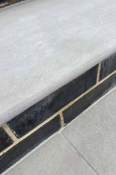 Close up of the bullnose of Florence Grey 20mm Moulded off the shelf Step next to black bricks, showing texture.***West Essex Landscapes, www.westessexlandscapes.co.uk
