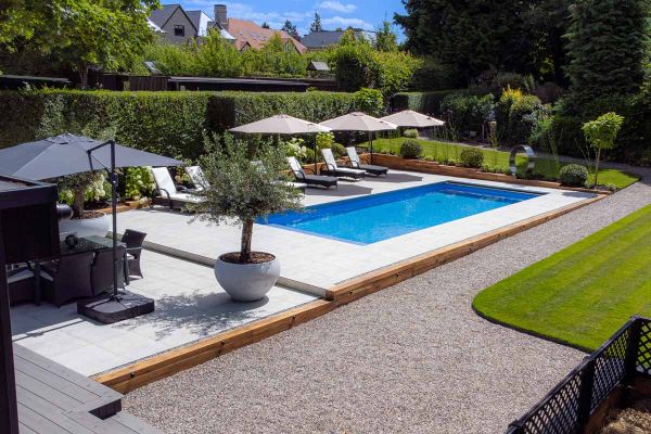 Side view of swimming pool area using light grey porcelain paving and 20mm bullnose steps and copings to match.***J Freeman Builds, www.jfreemanbuilds.co.uk
