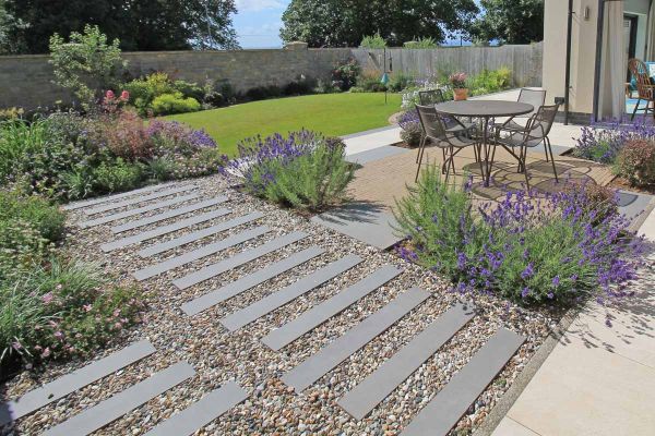 Views with lavender in the foreground and composite battens in the distance shows steel grey porcelain planks with inset pebbles.***Outerspace Creative Landscaping
