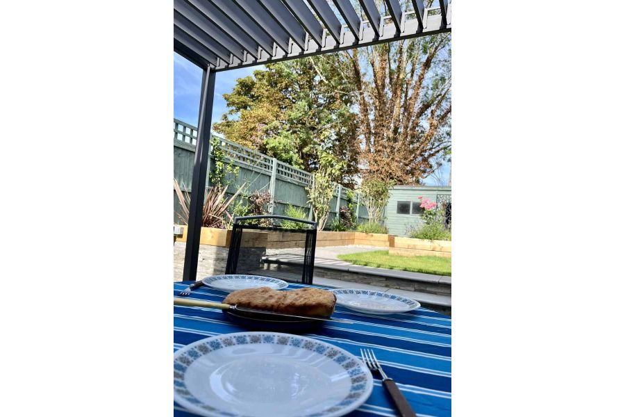 Alfresco view with plates set on blue table cloth under the proteus grey aluminium pergola with the louvres open.