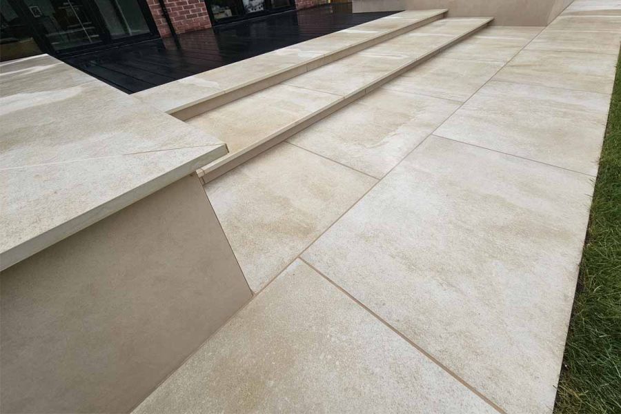 Almeria Beige Compact DesignClad used with very similar porcelain paving slabs, to clad rendered wall with steps leading to house.