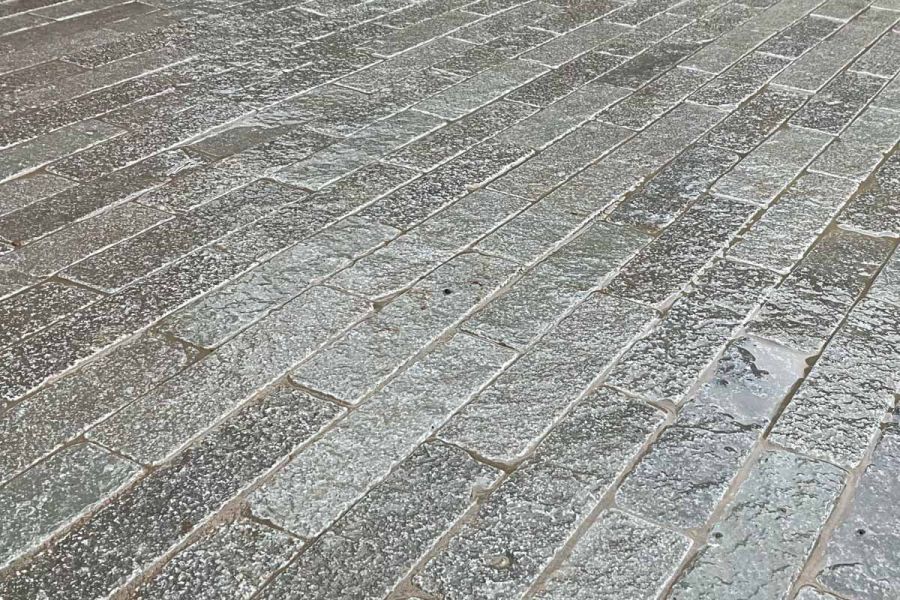 Captured in a close-up shot, the glistening surface of wet antique grey stone pavers reveal their smooth texture and inviting touch.
