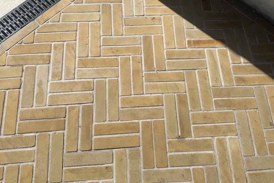 Close-up view of Harvest stone pavers arranged in a double herringbone design, displaying their textured surface and soft tones.