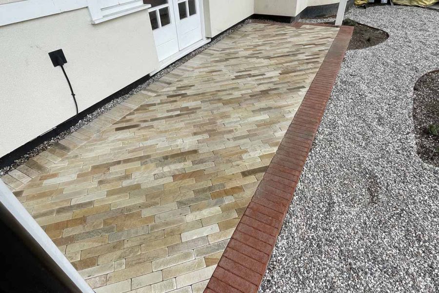 Detailed photograph showcasing Tumbled Mint Sandstone pavers as front entryway steps, surrounded by red pavers.