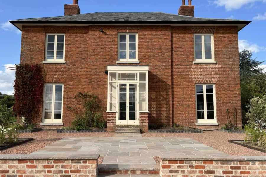 Centred view of traditional house using autumn brown indian sandstone paving, bullnose steps and copings.