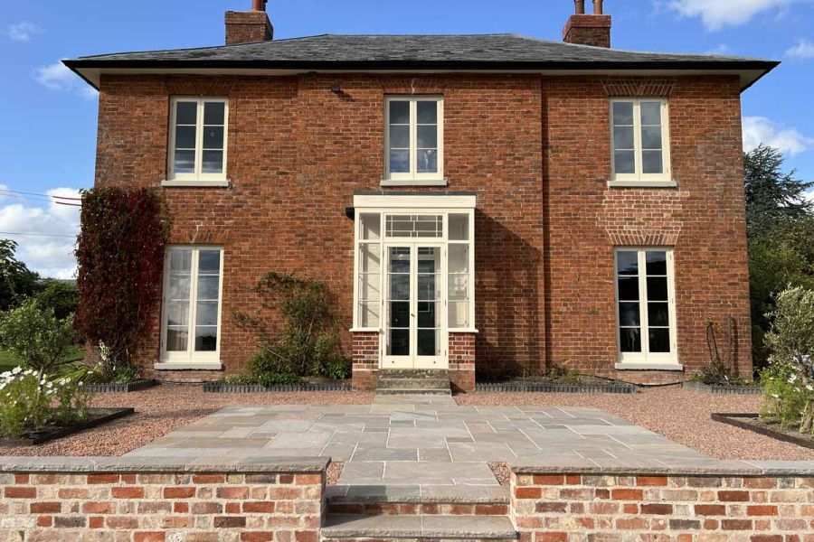 Centred view of traditional house using autumn brown indian sandstone paving, rock-faced steps and copings.