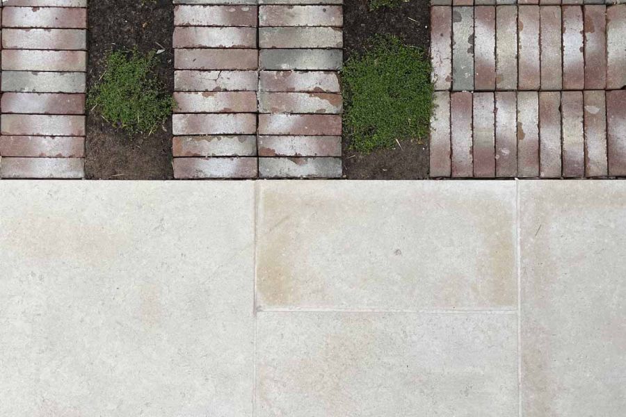 Split view of bexhill clay pavers and egyptian beige limestone with moss interspersed between the brick pavers.