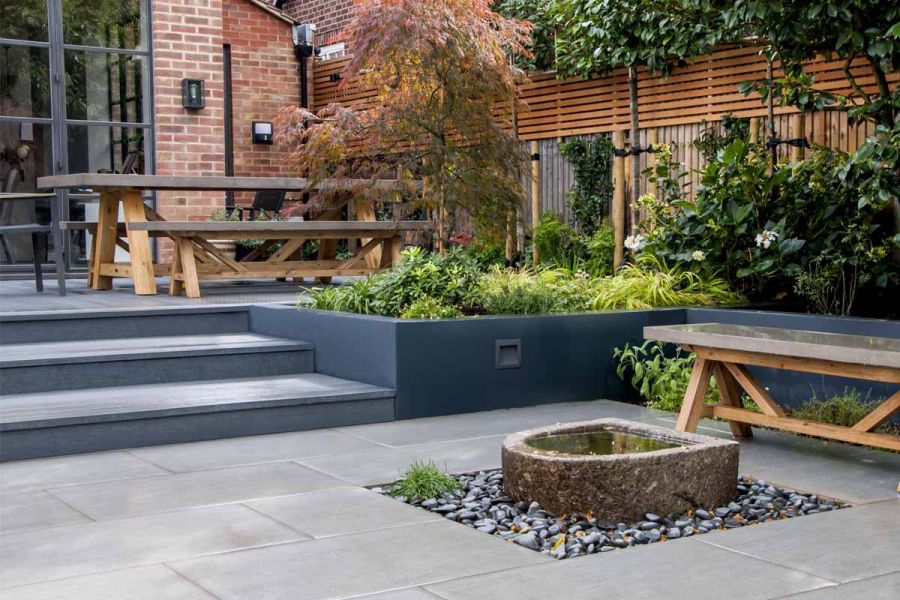 Two wooden benches sat on different levels with black basalt millboard decking used as steps leading up to french doors.