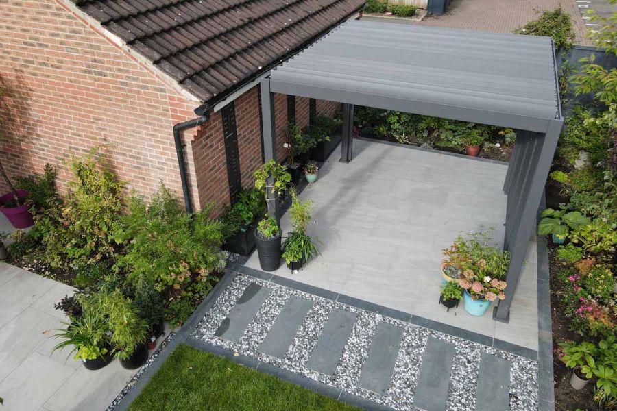 Kandla Grey patio broken up by charcoal porcelain planks used as stepping stones and to border the lawn.