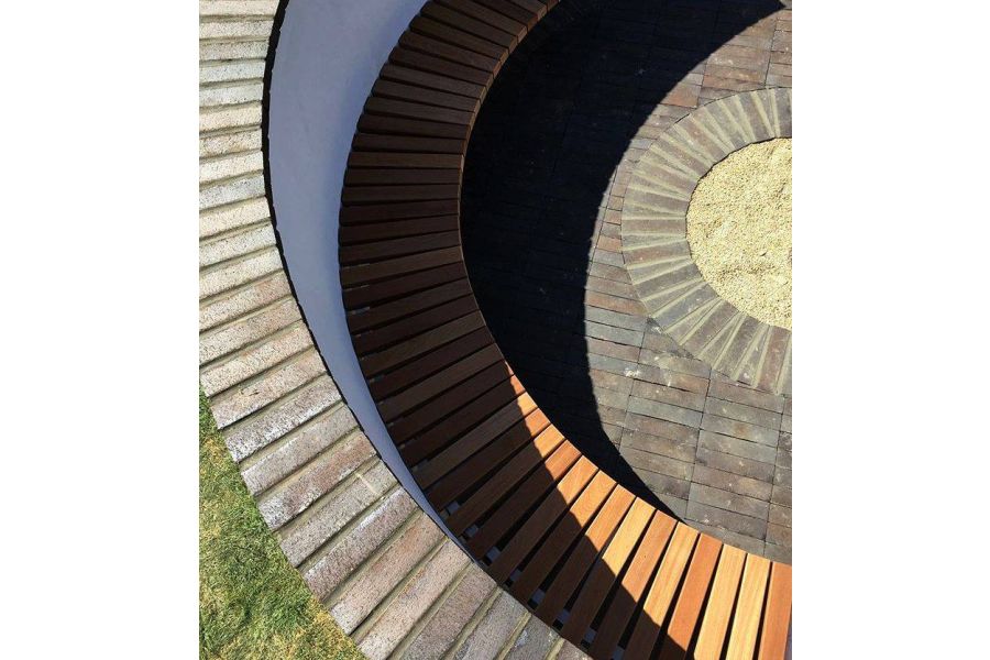 Curved sunken seating with unbound Chelsea clay pavers laid stackbond around mortared pavers cut to fit edge of circle of gravel.