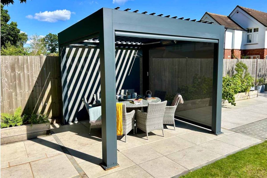 Anthracite Grey 3x3 Deluxe Metal Pergola in a garden setting, with louvres open and sunlight streaming onto a dining table below.