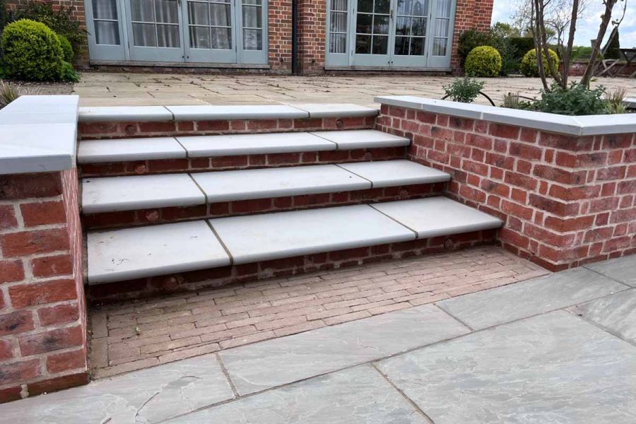4 Contemporary Grey Sawn Sandstone Steps lead from patio of sandstone and clay pavers up to house level patio.