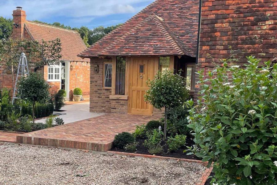 Cotswold Clay Paver Belgian Bricks used as entrance step to cottage-style house, with outhouse to the left.