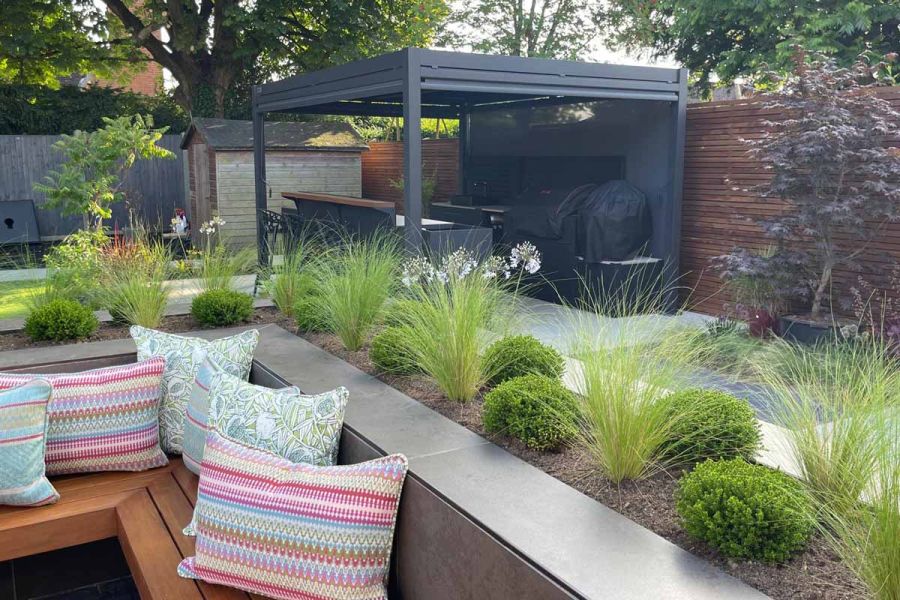 Pergola in distance with Dark Mocha exterior cladding used to create enclosed firepit with floating bench.