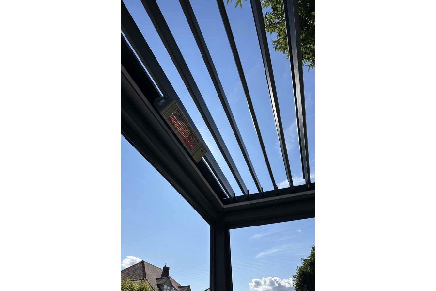 Close-up of the Deluxe Anthracite Grey metal Pergola's open louvres, framing a backdrop of trees and blue skies, available in 4x4.