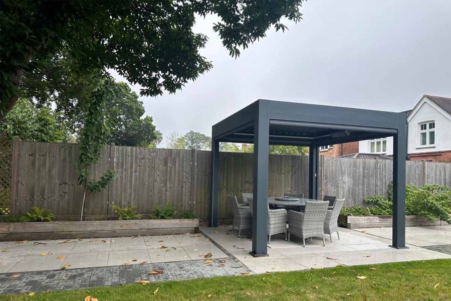 Outdoor seating area under the Deluxe Anthracite Grey 3x3 Metal Pergola, with adjustable louvres providing shade.