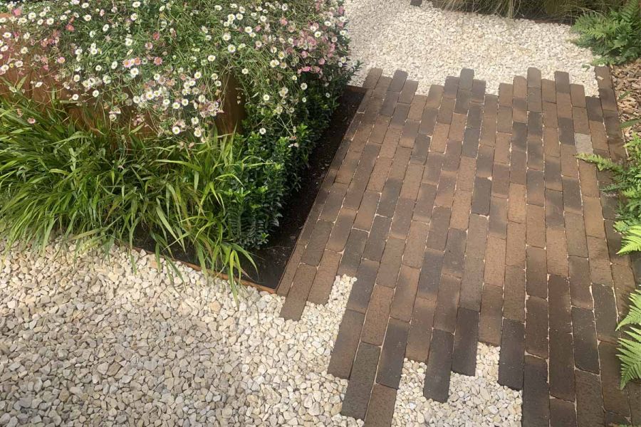 Silver Gilt medal winner at RHS Tatton Park Flower Show 2024 shows close view of derby clay pavers, pebbles and foliage.