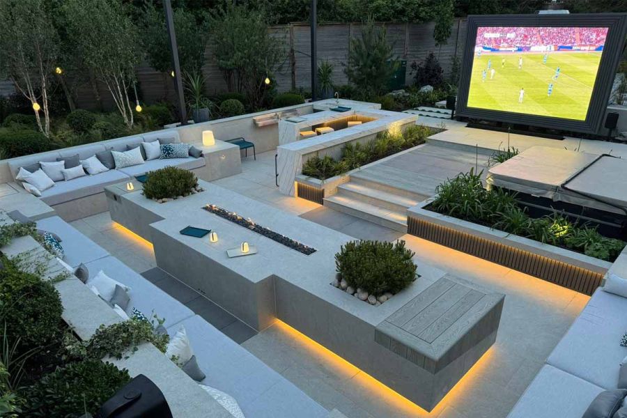 Stunning outdoor cinema area with built in sofas surrounding using astor grey porcelain paving, hot tub in the backgroud.