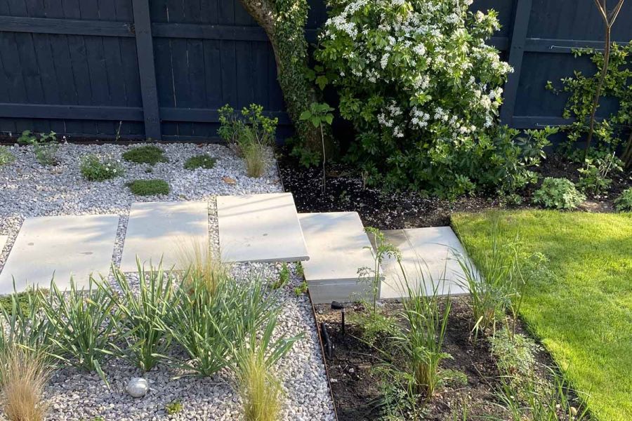 Stepping stones of Dove Grey Sandstone lead to a bullnose step down to a lawn. Garden step ideas by Katherine Lee Garden Design.