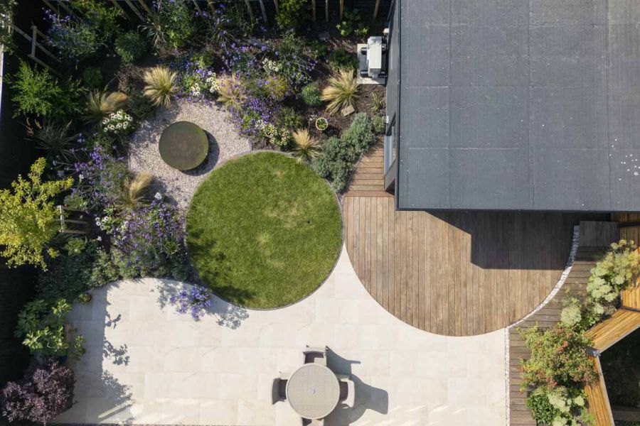 Birds eye view of modern garden design featuring circular patterns, purple and green plants and egyptian beige limestone paving.