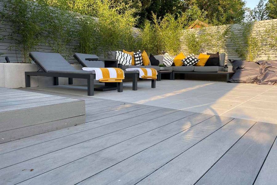 Pebble Grey Brushed composite fascia boards with matching steps, leading to a paved area with sunloungers and a corner sofa.