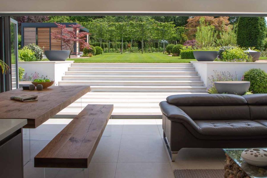 Glorious views of Faro Porcelain Steps with flat wall coping stones from inside, leading up to large lawn area. Design by Caroline Davy.