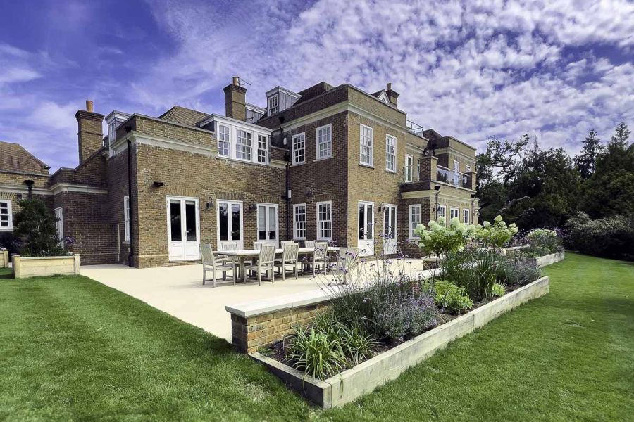 Large, impressive traditional house with big florence beige porcelain patio host to outdoor dining table and chairs.