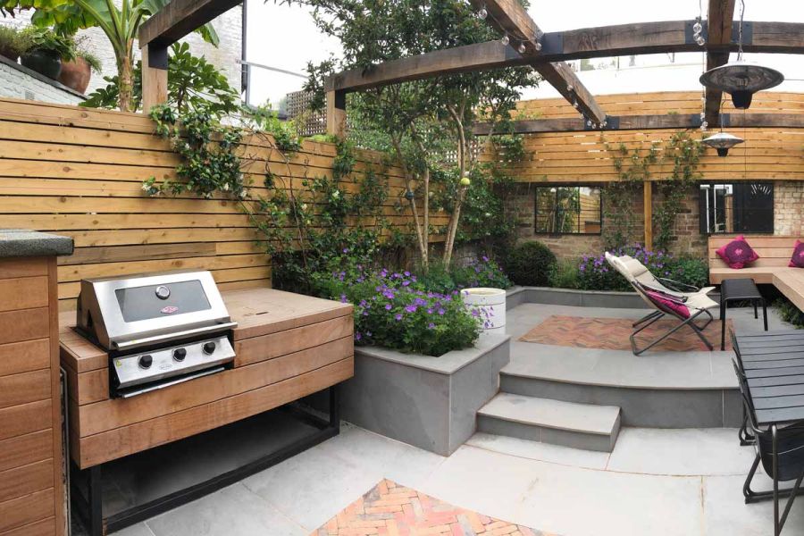 Florence Storm Porcelain Paving surrounds Clay Pavers in BBQ area, with more paving in an elevated space featuring a lounge chair.