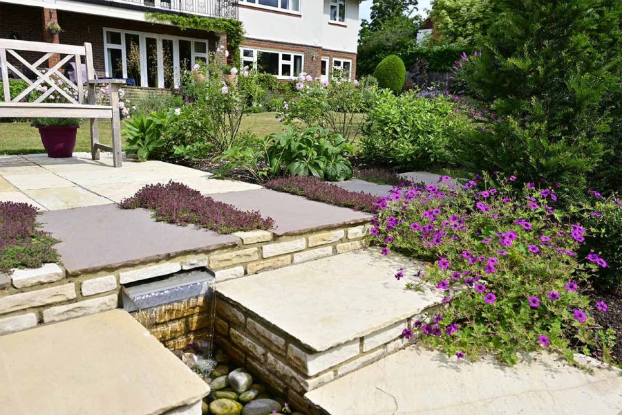 Design by Painted Fern, mint sandstone garden walling creates water feature paired with matching paving.