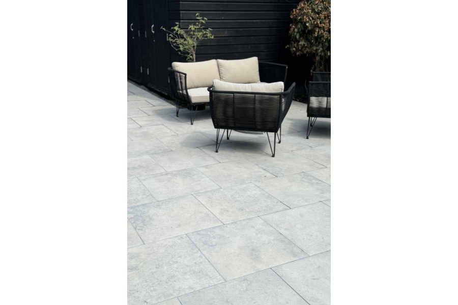 Portrait view of jura grey porcelain paving with rattan outdoor furniture in the background shows off unique markings.