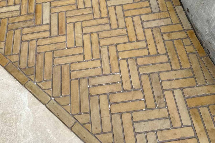 Detailed image of Harvest stone pavers laid in a double herringbone pattern, showcasing the sawn and tumbled texture and warm hues.