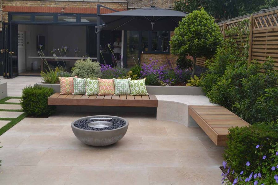 Firepit sits in the middle of small jura beige limestone patio with built in floating bench surrounding.