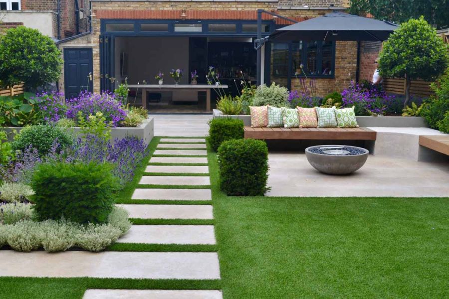 Small patio of jura beige limestone with bench surrounding firepit has staggered slabs leading off to lawn.