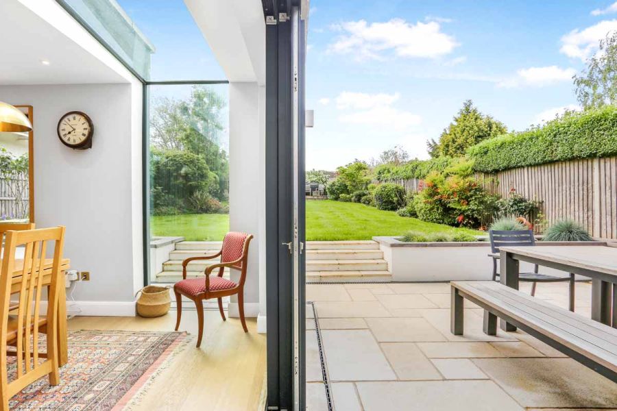 View split between indoors and outdoors through french doors shows antique cream sandstone patio with steaps leading to lawn.