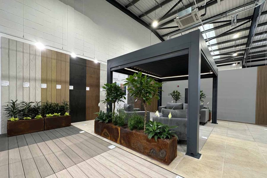 Anthracite grey Deluxe Pergola with a stylish lounge set beneath, creating a comfortable space in showroom setting.