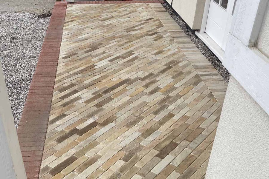 Up-close view of Tumbled Mint Sandstone pavers utilized for front entrance steps, with a border of red pavers.