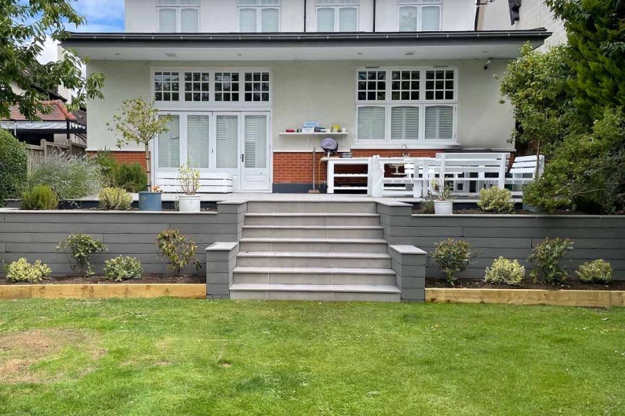 Centre view of white house with steps between built-in flowerbeds, clad in Pebble Grey Brushed composite fascia boards.