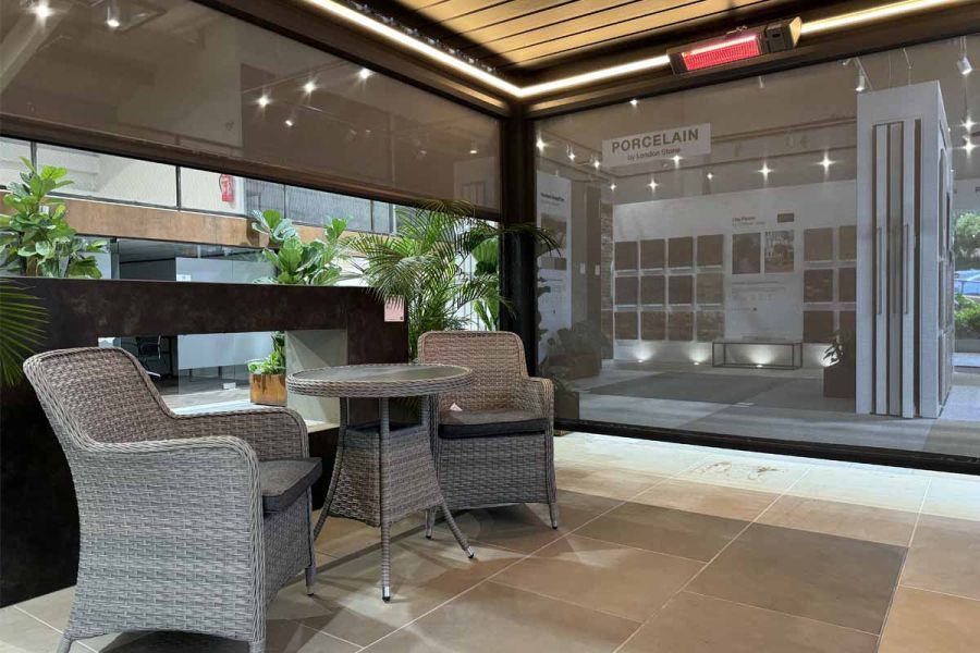 Anthracite Grey Deluxe Metal pergola standing in an open patio in a showroom, with motorised blinds for added privacy.