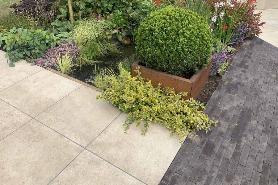 Close up shot of cream porcelain paving at RHS Tatton Park 2024, potted plants and clay pavers also in the shot.