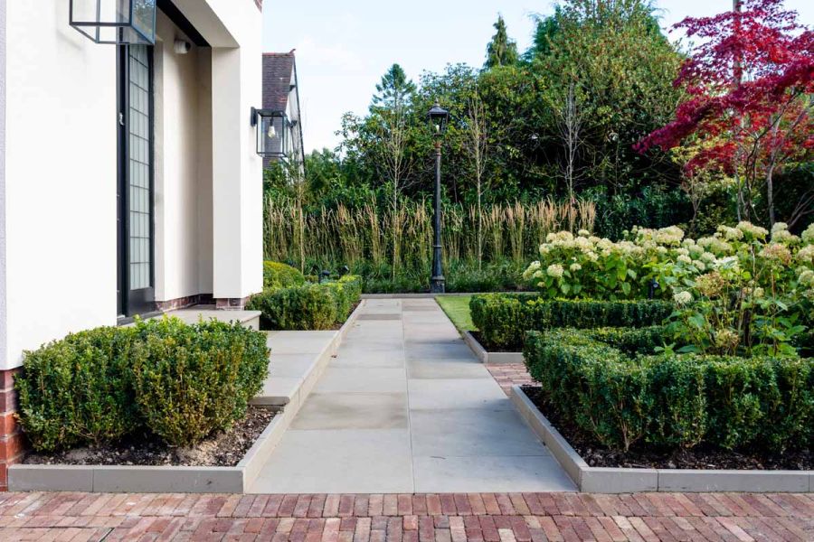Path of Heath Sandstone adjacent to clay paver patio, leads through hedges to front door, flanked by Heath Edging Stones.