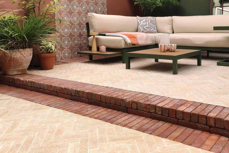 Limestone pavers laid on patio with seville clay pavers used as border and step up to outdoor sofa with terracotta plant pots.