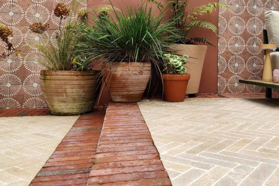 Four terra-cotta planters sit on different levels of patio using seville clay pavers as border and step up to another level.