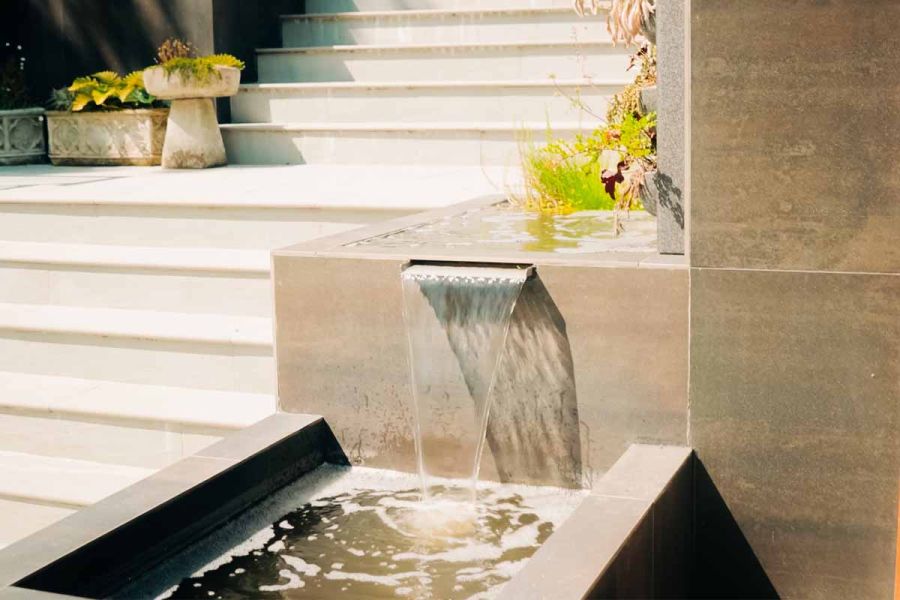 Huge outdoor staircase has steel dark porcelain cladding used on water feature leading down the bullnose steps.