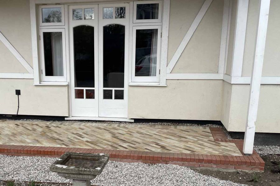 Tumbled Mint Sandstone pavers used as front entry steps to white double door, highlighted by red pavers along the border.