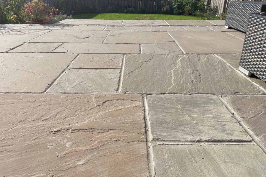 Low view of Tumbled Raj Green Sandstone patio with lawn in the distance showing natural variations with softened edges. 