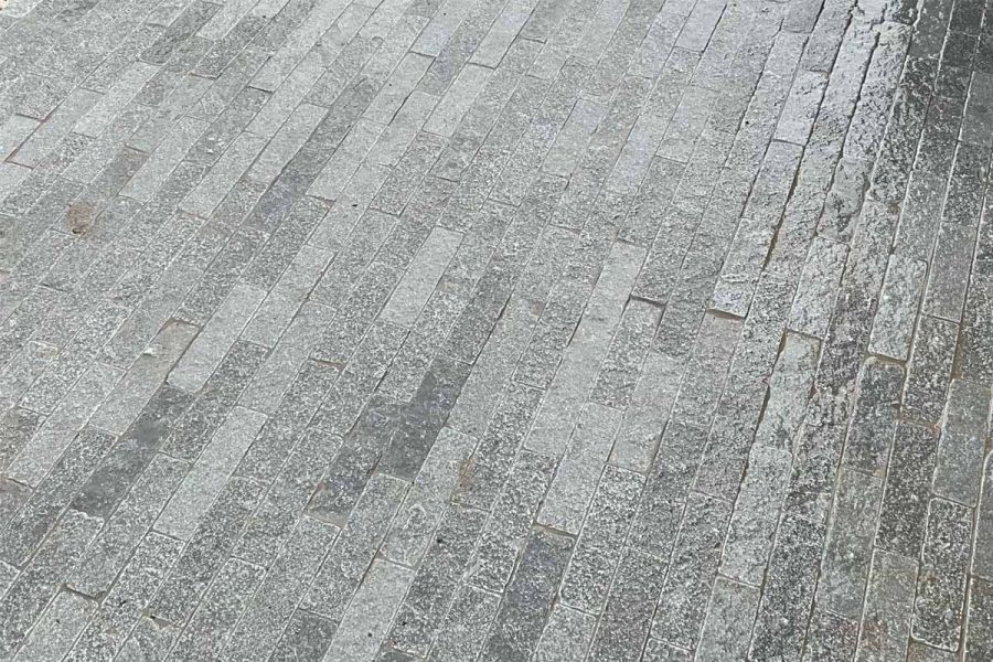 Glistening surfaces of Wet Antique Grey Stone Pavers reveal intricate patterns and subtle variations, and a range of grey tones