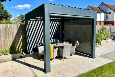 Anthracite Grey 3x3 Deluxe Metal Pergola in a garden setting, with louvres open and sunlight streaming onto a dining table below.***
