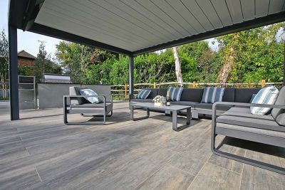 Wood Effect Porcelain paving slabs laid in planks underneath a large Renson pergola with grey garden lounging set.***Design by Karen McClure, www.karenmcclure.co.uk | Built by Esse Landscapes, www.esseland.co.uk
