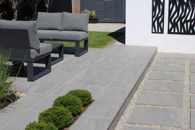 Staggered slabs in between pebbles lead to long step up to patio of kandla grey porcelain paving with modern outdoor furniture.***Oakleigh Manor, www.oakleighmanor.com
