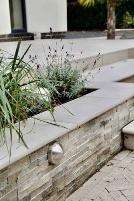 Close up of raised flowerbed clad with stone walling and capped with ash beige porcelain 20mm bullnose coping stones.***Nadine Mansfield Garden Design Ltd & Lenny Landscapes

